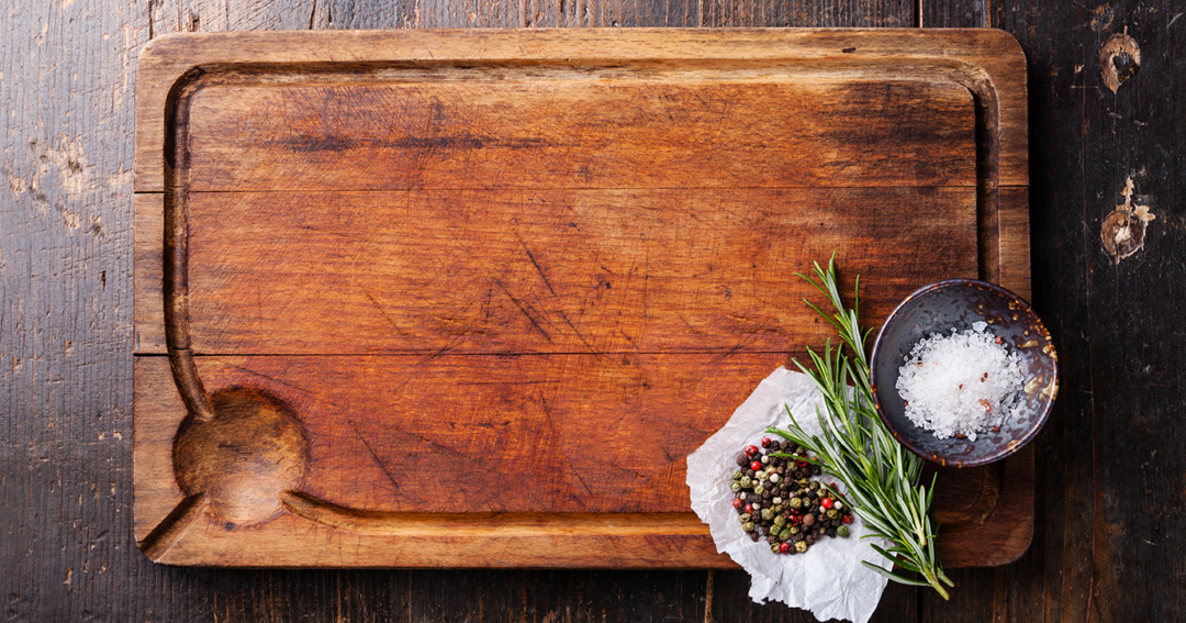 Wooden cutting board with rosemary, peppercorns, salt