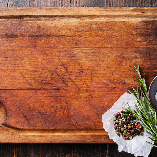 Wooden cutting board with rosemary, peppercorns, salt